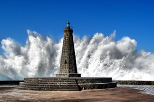 significativa imagen del impacto de las olas en el muelle de Bajamar con el faro en primer plano.