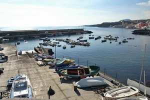 Un hermoso día soleado en el puerto de Candelaria con un muelle lleno de barcos almacenados allí.
