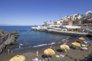 Esta foto muestra la pequeña playa de arena volcánica negra 'Playa Chica' en Puerto Santiago en Los Gigantes