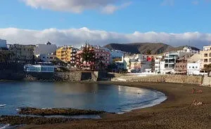 playa-Las-Maranuelas_CanariasLife_ Pueblo costero con edificios coloridos, playita y montañas en el fondo.